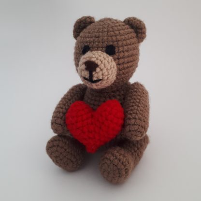 Crocheted teddy bear holding a big red heart
