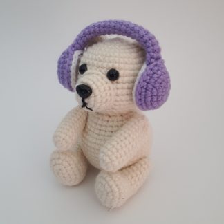 Crocheted polar bear wear a set of purple crocheted earmuffs.